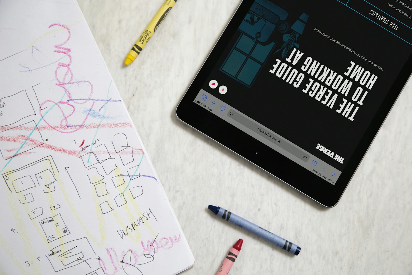 Na biurku leżą tablet i szkicownik projektowy.